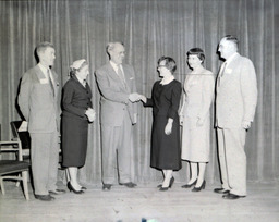 UBEA--Smead Award Granted to Ruth Platzke Apr. 12, 1957: Three Men, Three Women Standing, Man Shaking Hands with Ruth Platzke