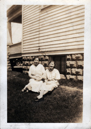 Two Women Sitting Outside of House