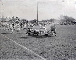 Football ca. 1960: Action Photo of #47 Running with Ball and #84 Trying to Tackle Him