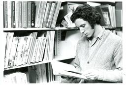 Student Posing with Book in Library Stacks (Part of the NMU Historic Photographs Collection)