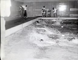 NMC Swimming--NMC vs. Green Bay--YMCA Feb. 25, 1961: People Swimming in Indoor Pool with Five Men Watching