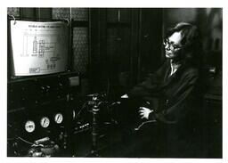 Student Working with Machine and Looking at Double-Acting Cylinder Circuit Chart (Part of the NMU Historic Photographs Collection)